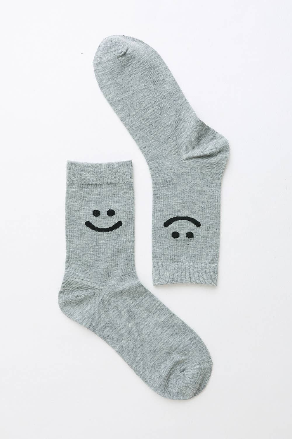 Pair of light gray crew socks with smiley and sad face design on white background