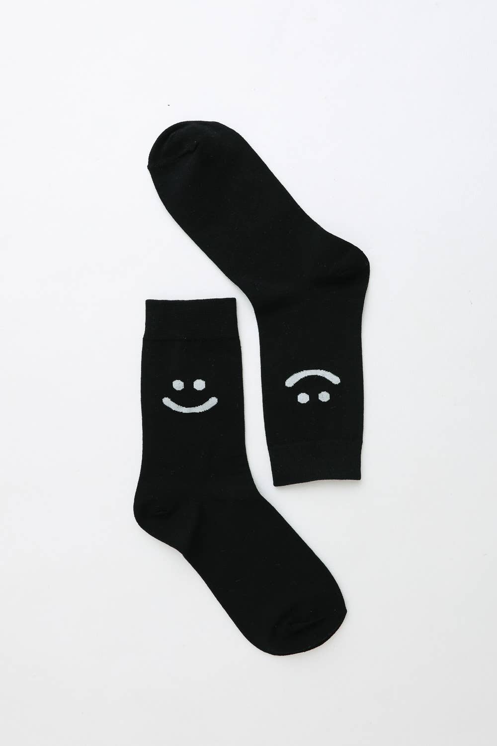 Pair of black crew socks with smiley and sad face design on white background