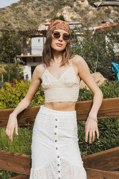 Woman in boho outfit with white button skirt, lace top, and rust paisley bandana outdoors