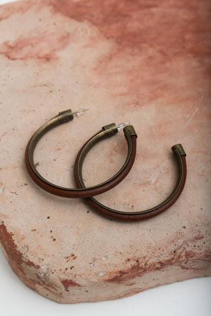 Bronze hoop earrings displayed on a textured stone surface.