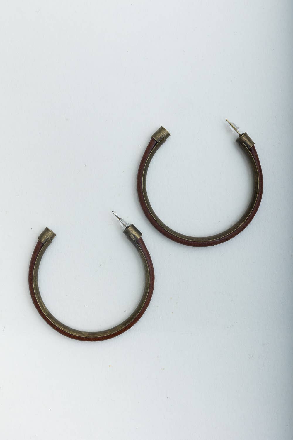 Pair of brown hoop earrings with metal posts on a white background.