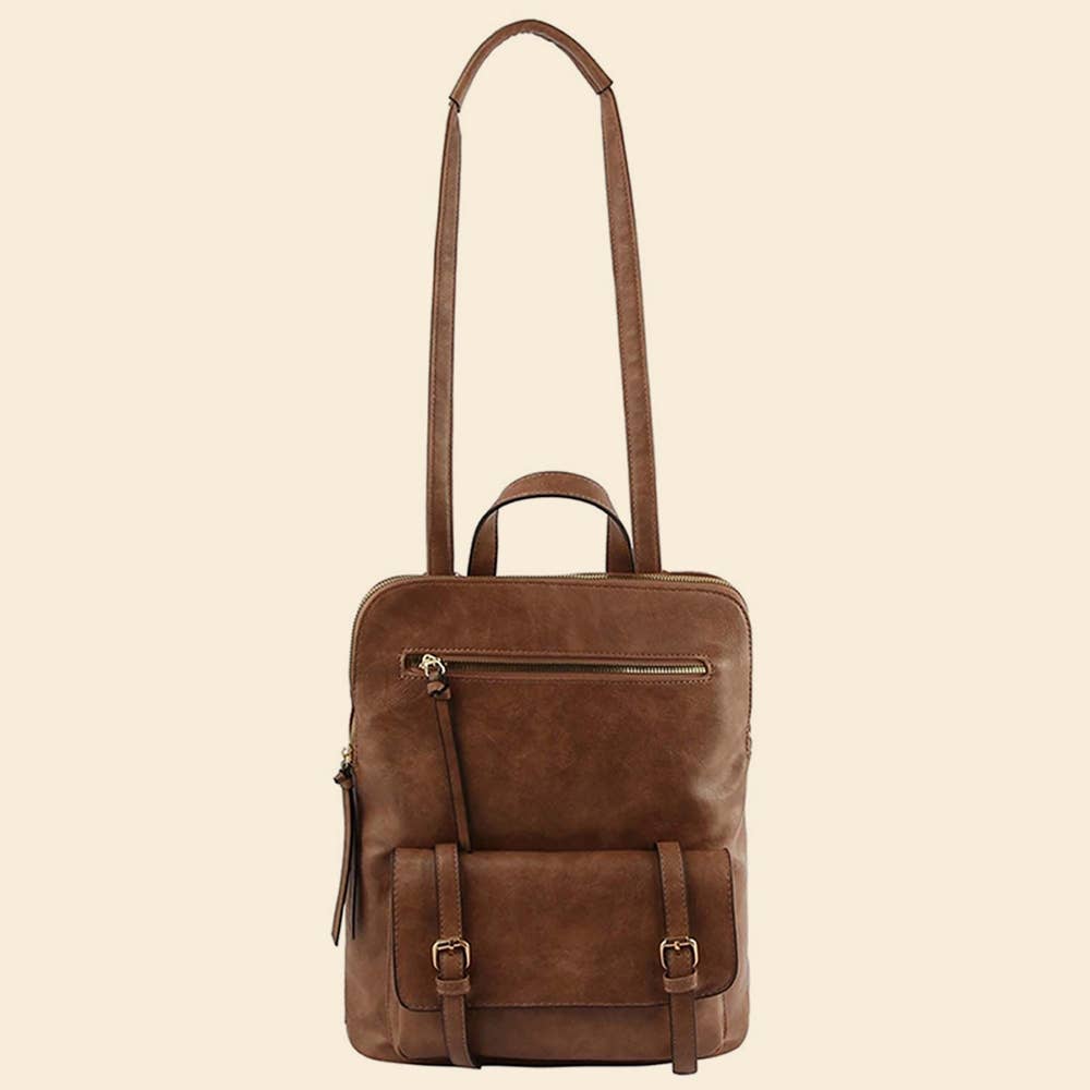 Brown leather backpack with long adjustable crossbody strap displayed on a beige background.