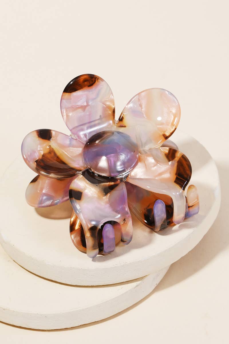 Close-up of a purple and brown tortoise shell acetate floral-shaped hair clip displayed on a white surface.