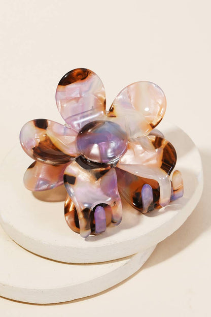 Close-up of a purple and brown tortoise shell acetate floral-shaped hair clip displayed on a white surface.