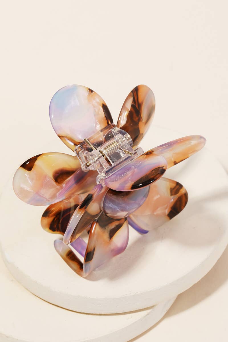 Back view of a tortoiseshell and purple acetate floral-shaped hair clip with claw clasp on a white surface.
