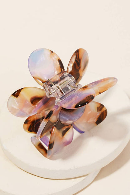 Back view of a tortoiseshell and purple acetate floral-shaped hair clip with claw clasp on a white surface.