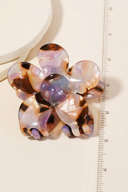 Multicolored tortoiseshell and purple acetate floral-shaped hair clip shown next to a ruler for scale on a light background.