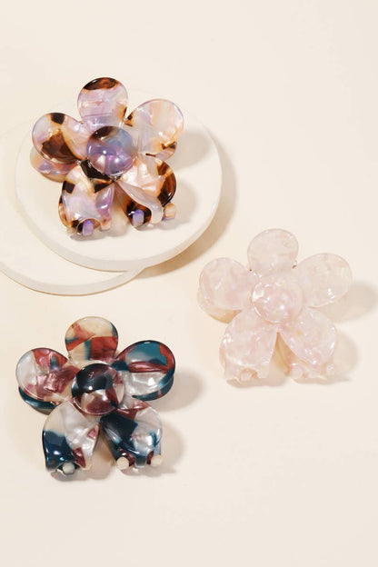 Set of three multicolor floral-shaped acetate hair clips in pink, purple, and blue tones displayed on a beige background.