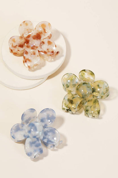 Set of three floral-shaped acetate hair clips in blue, green, and tortoise shell colors displayed on a beige background.