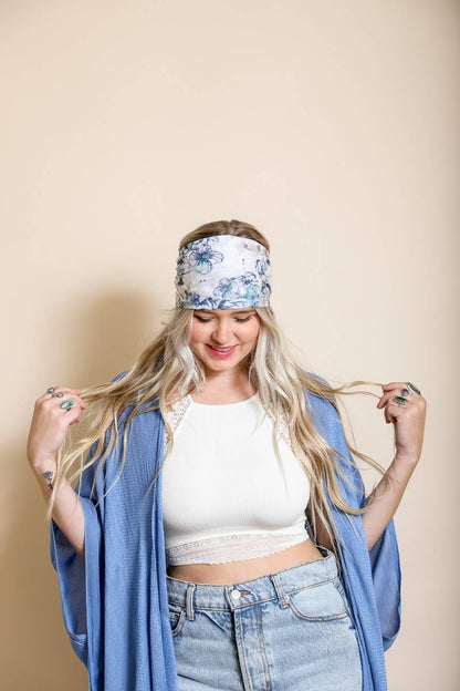 Woman wearing a blue floral headband, white crop top, and denim with a beige backdrop