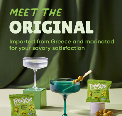 Freestyle Snacks Original Green Olives packaging displayed with cocktails and loose olives on a dark green background.