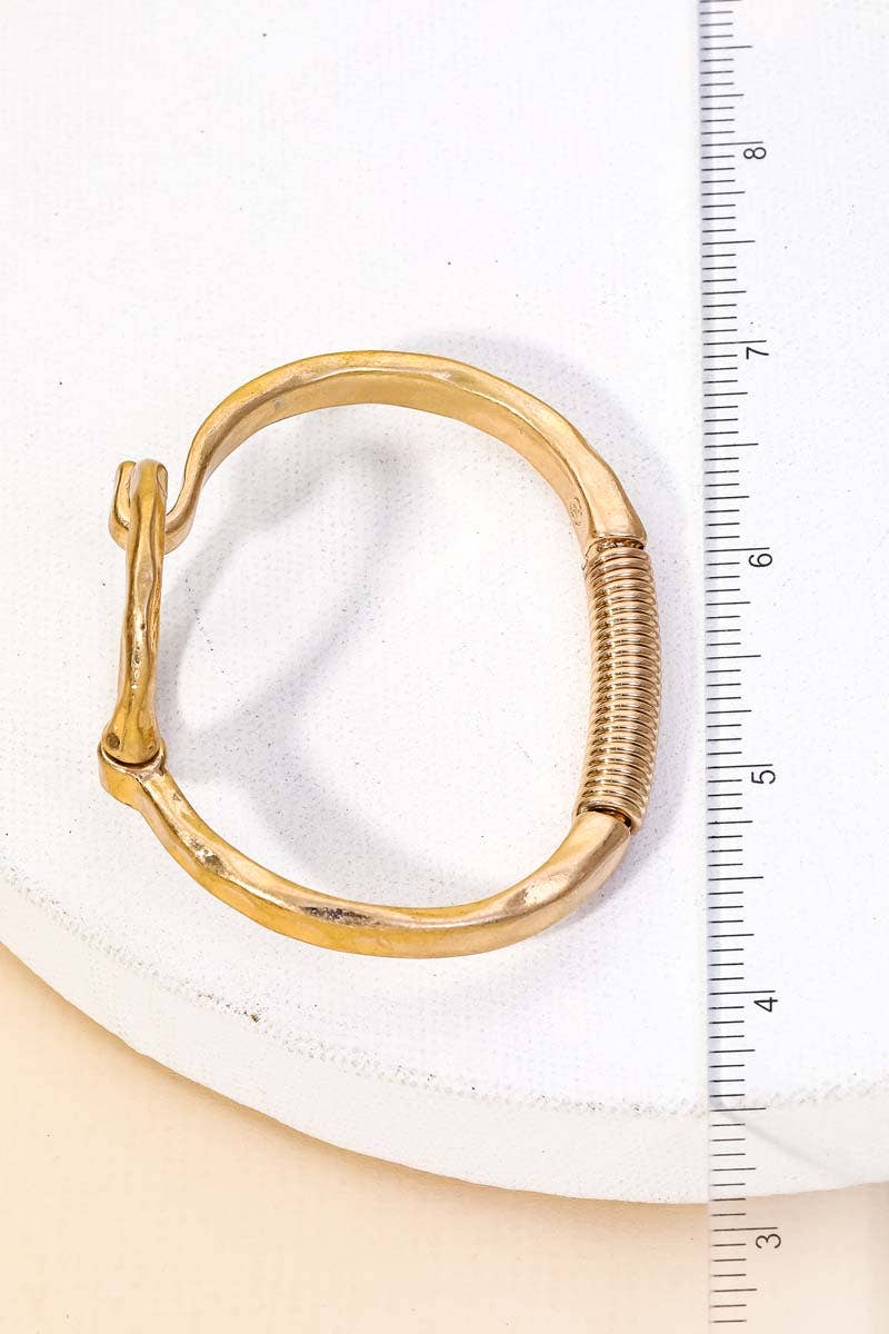 Gold circle bracelet displayed on a white cushion with ruler for size reference.