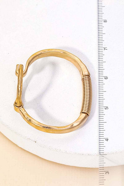Gold circle bracelet displayed on a white cushion with ruler for size reference.