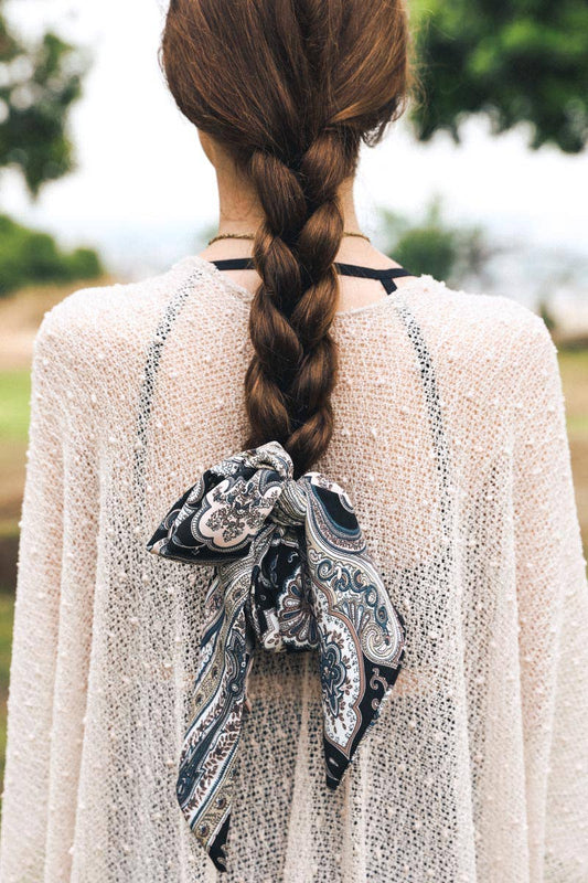 Woman with braid tied back with a navy and white paisley scarf in bow style outdoors