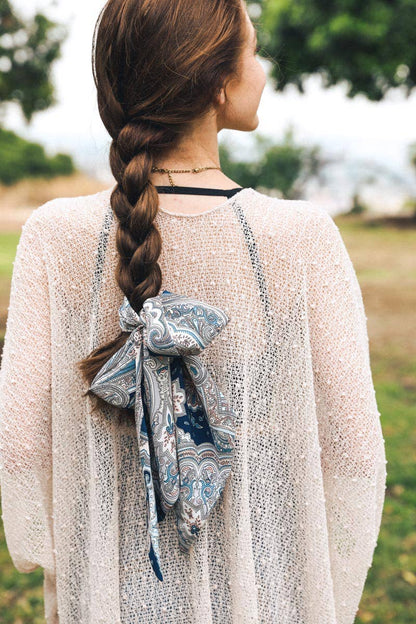 Woman with braided hair tied back with a paisley scarf in a bow outdoors