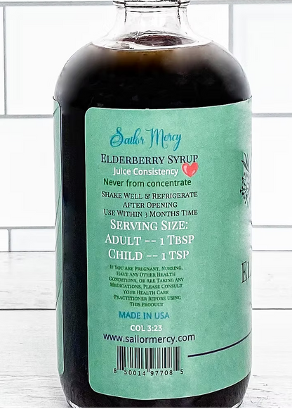 Sailor Mercy Elderberry Syrup 8 oz glass bottle back label showing serving size, nutrition details, and storage instructions on teal background.