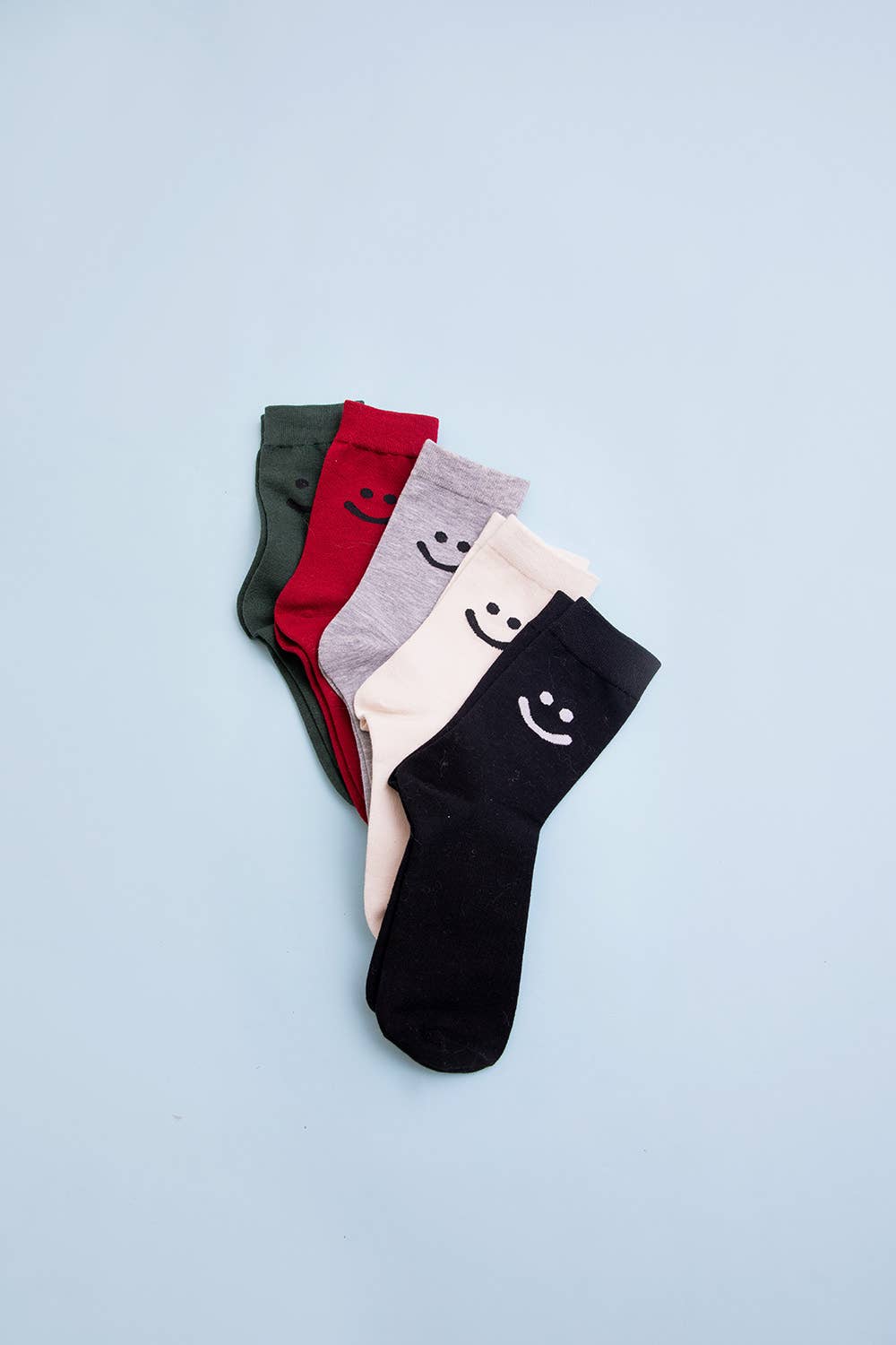 Set of five smiley face crew socks in black, cream, gray, red, and green, displayed on light blue background