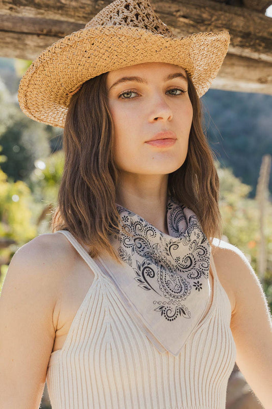 Woman in straw hat with paisley bandana scarf and blurred natural background