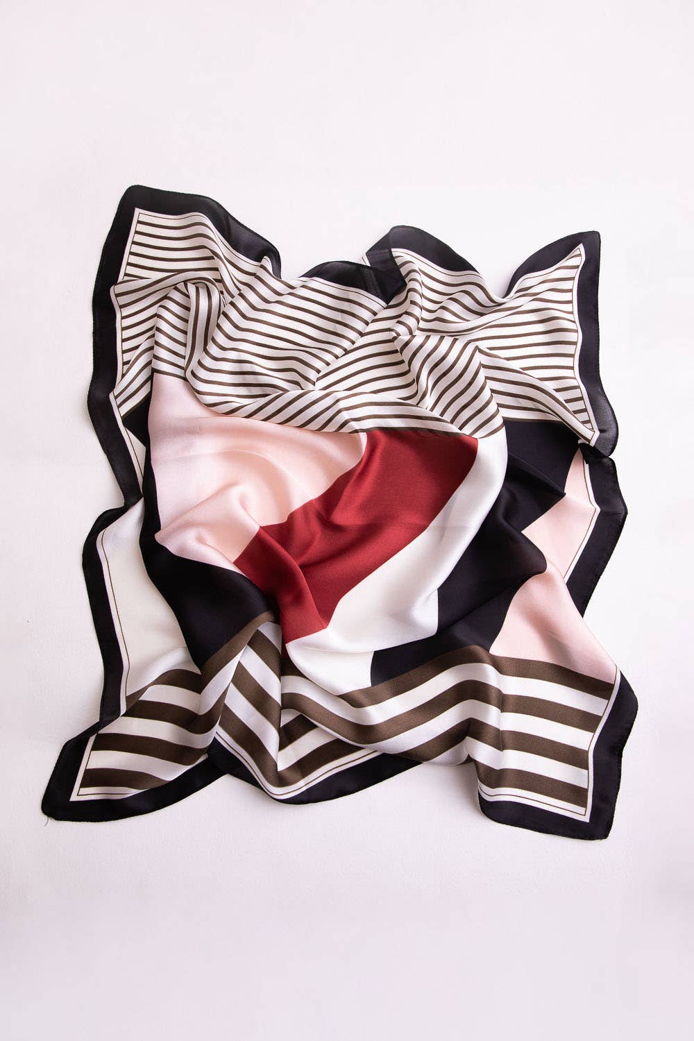 Flat lay of black, white, and red striped scarf on white background