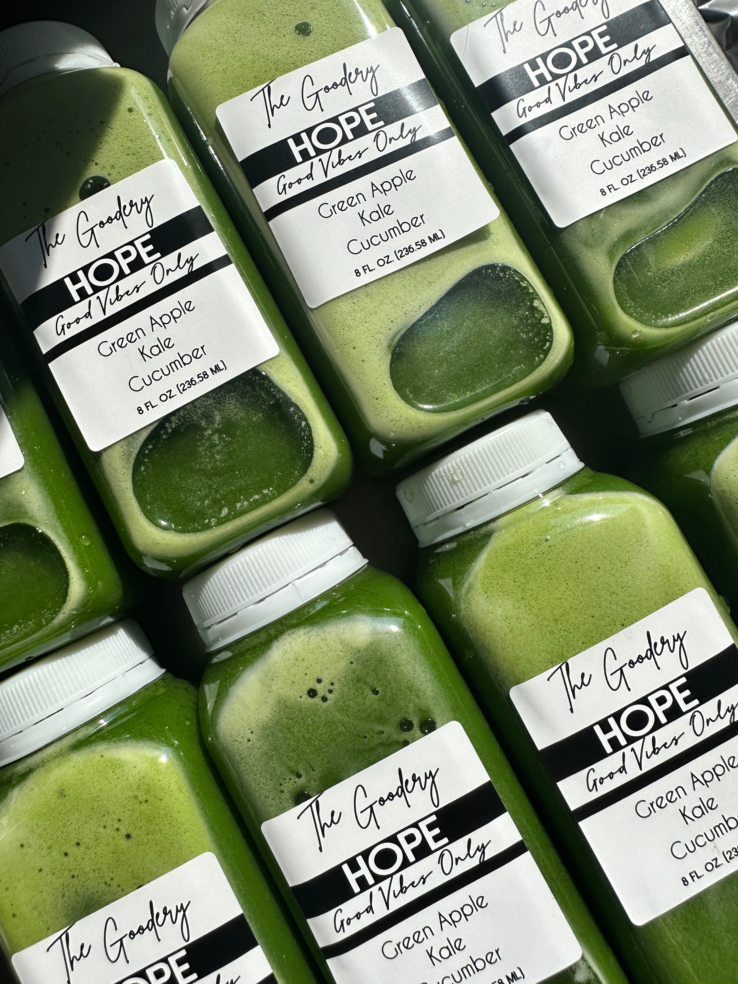 The Goodery HOPE green juice bottles labeled Green Apple, Kale, and Cucumber, arranged closely together.