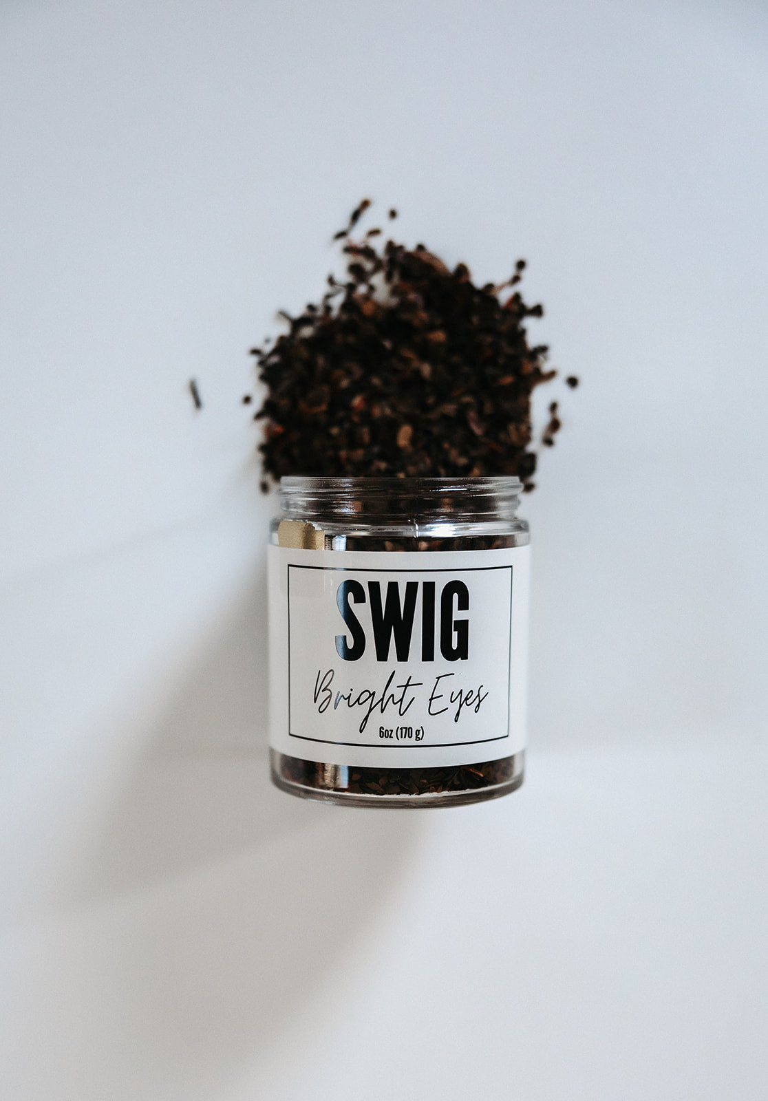 Loose Bright Eyes tea spilling from a Swig jar with branded label on white background.