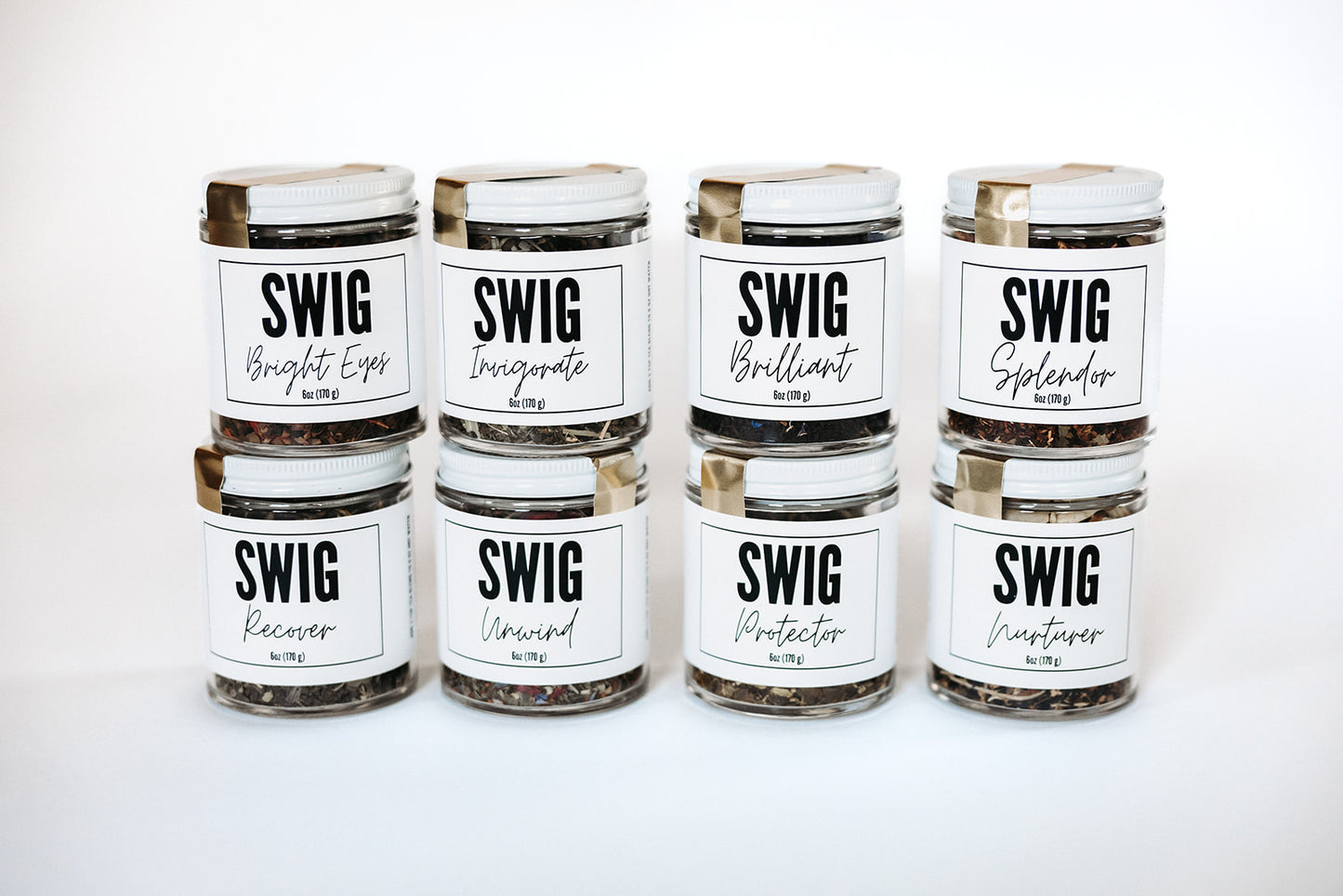 Eight SWIG loose leaf tea jars arranged in two rows on a white surface, featuring The Goodery’s artisan tea blends.