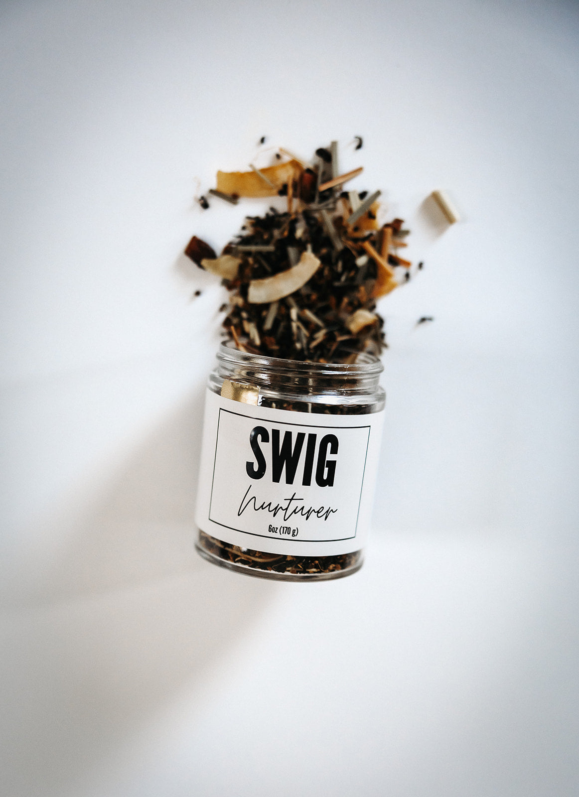 Loose leaf Nurturer tea cascading from a branded Swig jar on a white background.
