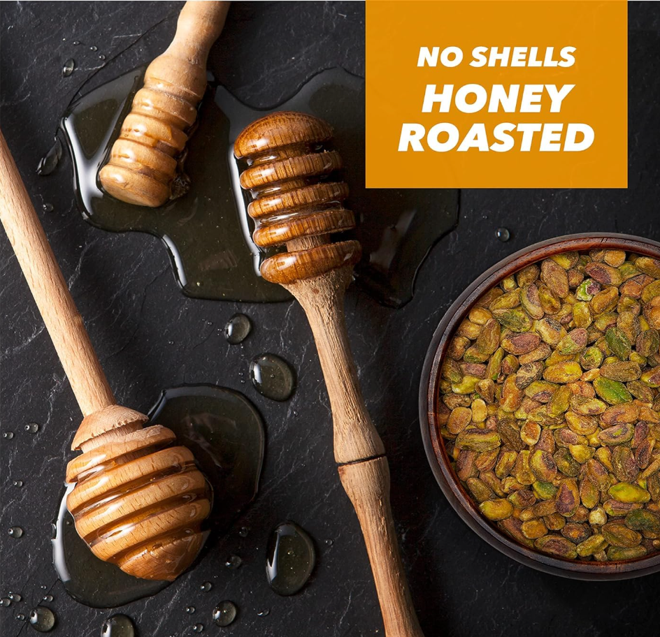 Bowl of Wonderful No Shells Honey Roasted Pistachios with honey drizzles and wooden honey dippers on a dark surface.