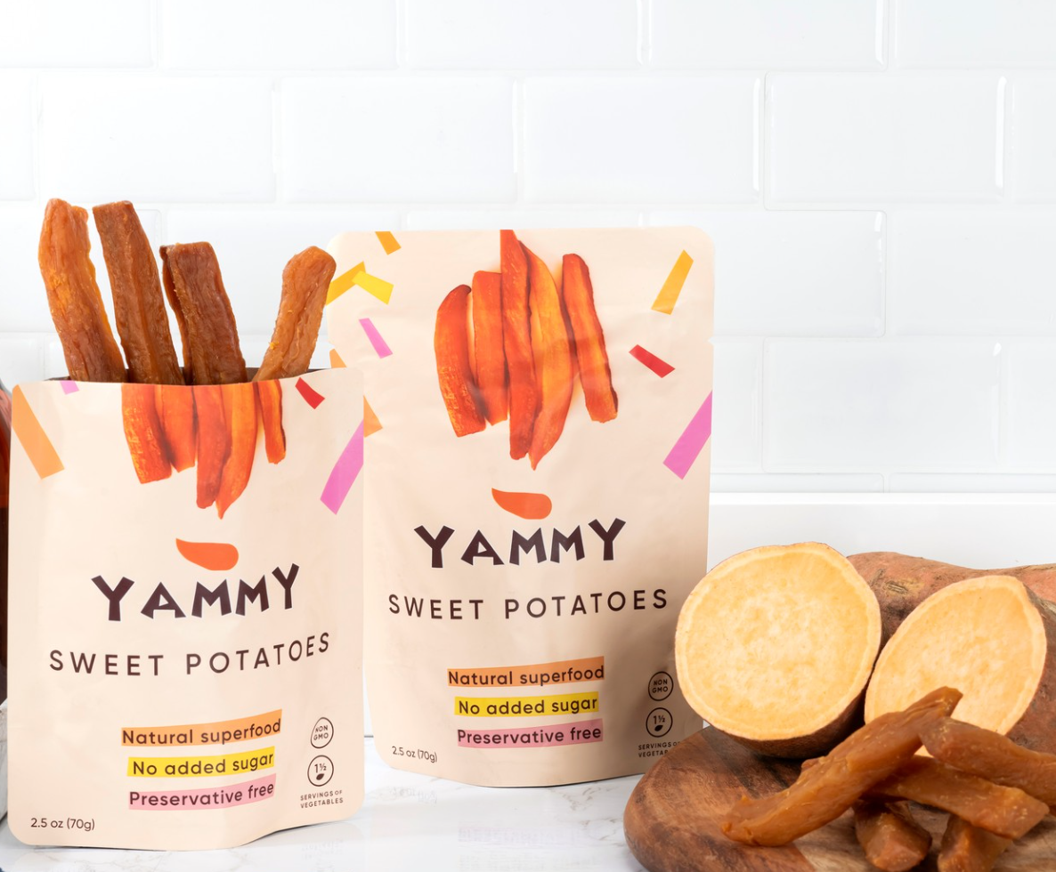 Yammy Sweet Potatoes packaging with sweet potato sticks and sliced fresh sweet potatoes on a wooden board.