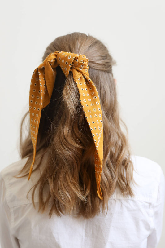 Back view of woman wearing yellow patterned headscarf
