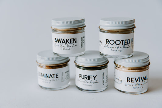 The Goodery adaptogen powder jars displayed in a stacked arrangement, featuring Awaken Maca Root, Rooted Ashwagandha, Luminate Schisandra Berry, Purify Chlorella, and Revival Lion’s Mane.